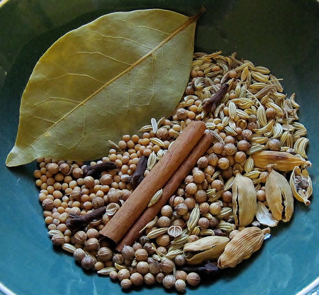 A selection of whole Indian spices including cinnamon, cardamom, cloves and bay leaf